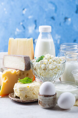 Fresh dairy products, milk, cottage cheese, eggs, yogurt, sour cream and butter on blue background