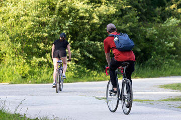 Fototapeta na wymiar Two cyclist riders on an asphalt track on a warm summer day, rear view