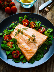 Steamed salmon fillet with vegetables on wooden table