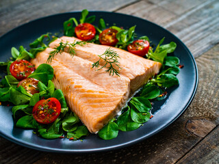 Steamed salmon fillet with vegetables on wooden table