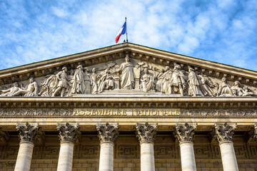Fototapeta premium Low angle view of the pediment of the Palais Bourbon, seat of the french National Assembly in Paris, France, bearing the inscription Assemblée Nationale in golden letters.