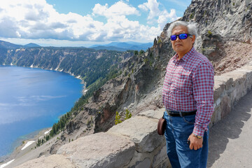 A retired asian man is out on a holiday in beautiful nature. Happy vacation time at Crater Lake, Oregon.