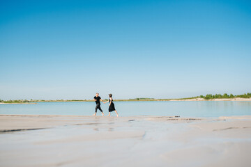 Fototapeta na wymiar young couple a guy with a girl in black clothes are walking on the white sand
