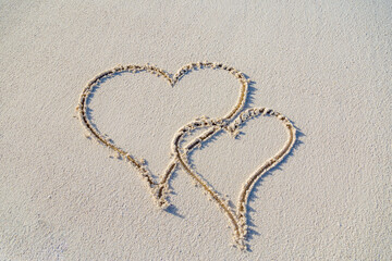 Two hearts drawn in white sand, love concept. Honeymoon or anniversary travel concept. Summer holiday vacation for couples