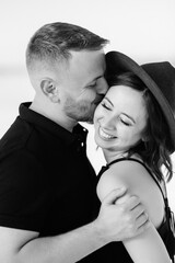 young couple a guy with a girl in black clothes are walking on the white sand