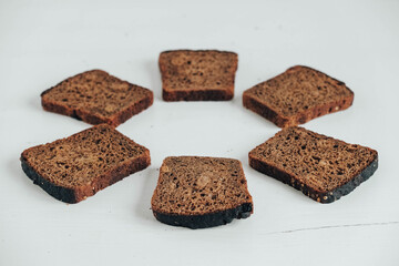 Slices of fresh brown bread with raisins on a white wooden background. Top view. Copy, empty space for text
