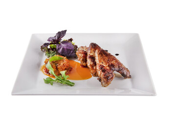 Grilled chicken wings with lettuce leaves on a white plate. 