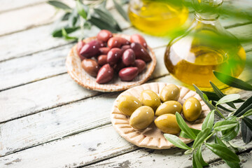 Variety of black and green olives and olive oil in bowls on white background close up