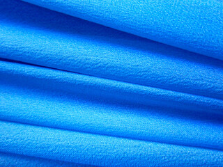 Artificial chiffon, fabric made of synthetic fibers. Thin blue draped fabric.