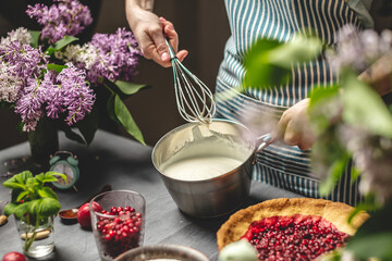 Cooking homemade cranberry pie. Pastry chef is whipping up a whisk of sour cream