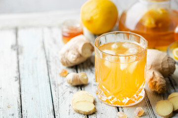 Yellow drink with ginger, lemon and ice in a glass, refreshing homemade ginger lemonade or ale on...