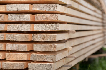 Stack of new wooden studs at a lumber yard, warm color,