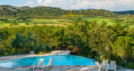Private outdoor luxury swimming pool overlooking the beautiful mountain views. Holiday, relax, vacantion. Lovely pool in the garden area, surrounded by plants. Auvergne ‐ Rhone ‐ Alpes, France.