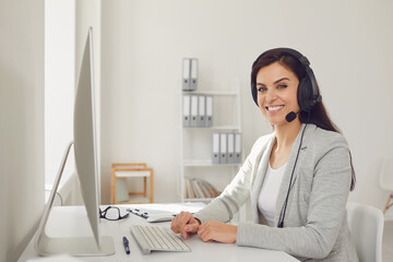 Call center operator woman in headset sitting at a computer in the workplace. Concept help desk...