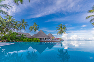 Tropical swimming pool with infinity sea view and palm trees and luxury water villas. Exotic travel and summer holiday vacation background destination. Maldives paradise island beach, ocean view