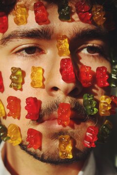 Human with every colour, but does not taste, portrait of a young man with gummy bears attached to face