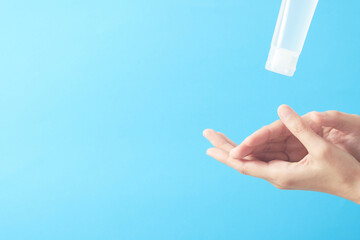 Close up woman hands using wash hand sanitizer gel in blue background.