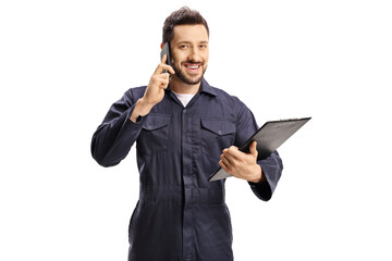 Male worker in a blue uniform talking on a mobile phone and holding a clipboard