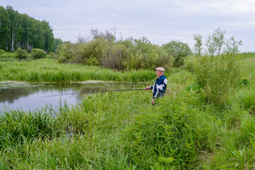 an elderly fisherman is fishing in a small river