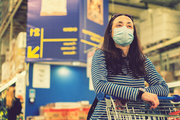 Fototapeta premium Asian young woman wearing a hygiene protective mask over her face while walking at the crowded shopping mall. Covid19 influenza in crowded place. woman wearing a mask in the supermarket. toned