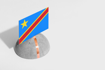 Congo flag tagged on rounded stone. White isolated background. Side view minimal national concept.