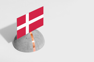Denmark flag tagged on rounded stone. White isolated background. Side view minimal national concept.