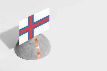 Faroe Islands flag tagged on rounded stone. White isolated background. Side view minimal national...