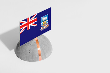 Falkland Islands flag tagged on rounded stone. White isolated background. Side view minimal...