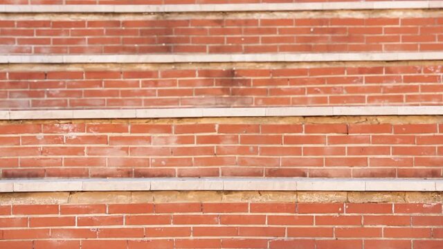 Uomo moro con giacca e occhiali da sole si muove ballando tra i gradini a mattoncini rossi