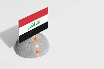 Iraq flag tagged on rounded stone. White isolated background. Side view minimal national concept.