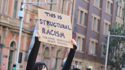 Sydney, NSW / Australia - June 6 2020: Black Lives Matter March. Protesting Aboriginal rights  death of. Sign reading 'This is structural racism, colonial oppression never stopped'.