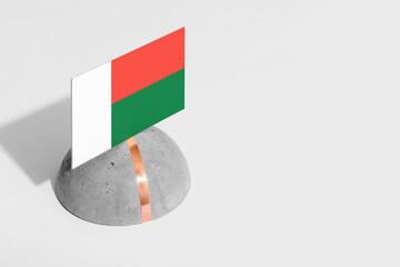 Madagascar flag tagged on rounded stone. White isolated background. Side view minimal national concept.