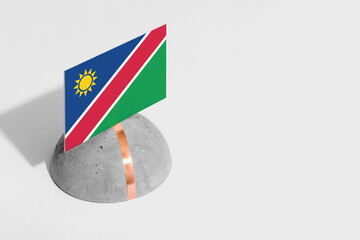 Naklejka premium Namibia flag tagged on rounded stone. White isolated background. Side view minimal national concept.