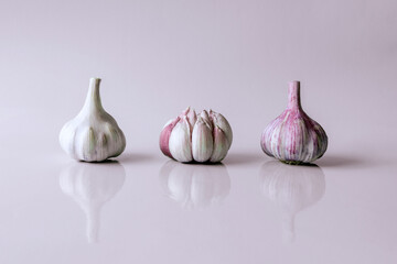 three heads of garlic on pink background