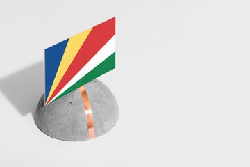 Seychelles flag tagged on rounded stone. White isolated background. Side view minimal national...