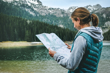 Traveler with map relaxing outdoor with rocky mountains on background. Summer vacations and...