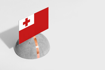 Tonga flag tagged on rounded stone. White isolated background. Side view minimal national concept.