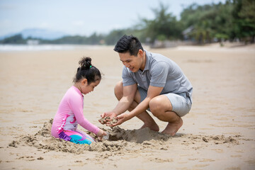 Girl and dad playing sand on the beach