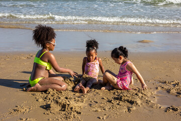 Cute kids having fun on sandy beach in summertime