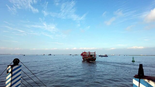 Vietnamese port of Hai Phong with red fishing vessel passing by on cloudy day, Handheld shot