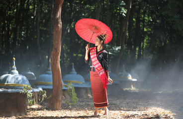 Esan Tribe women and children standing in forest with red umbrella, Thailand 