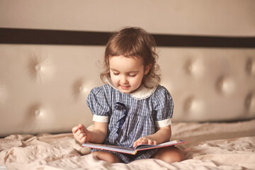 Naklejka premium Small cute girl in a retro dress reading a book.