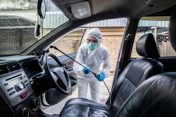 Professional cleaning staff with a To wear protective medical mask and PPE suit use chemical sprayer protect decontamination indoors. remove bacterias, viruses, and infections from the surface. COVID-