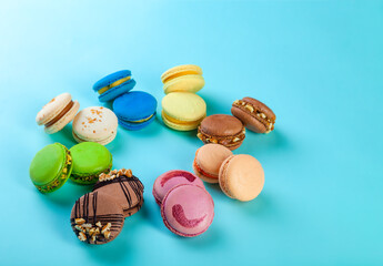 Different types of colorful sweet macaroons dessert on blue background