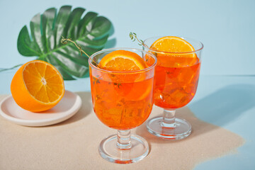 Glasses with fresh homemade orange sweet iced tea or cocktail, lemonade with thyme. Refreshing cold drink. Summer party.
