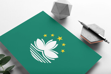 Macao flag on minimalist paper background. National invitation letter with stylish pen on stone. Communication concept.