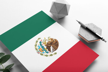 Mexico flag on minimalist paper background. National invitation letter with stylish pen on stone. Communication concept.