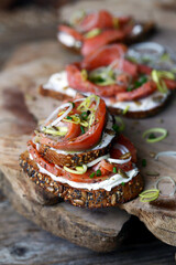 abrindo um sanduíche de pão de cereais, queijo macio e salmão defumado.