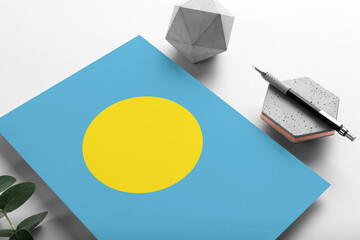 Palau flag on minimalist paper background. National invitation letter with stylish pen on stone. Communication concept.