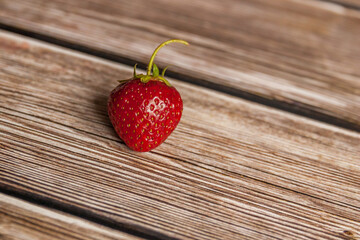 
One ripe strawberry berry on a wooden table close-up.
